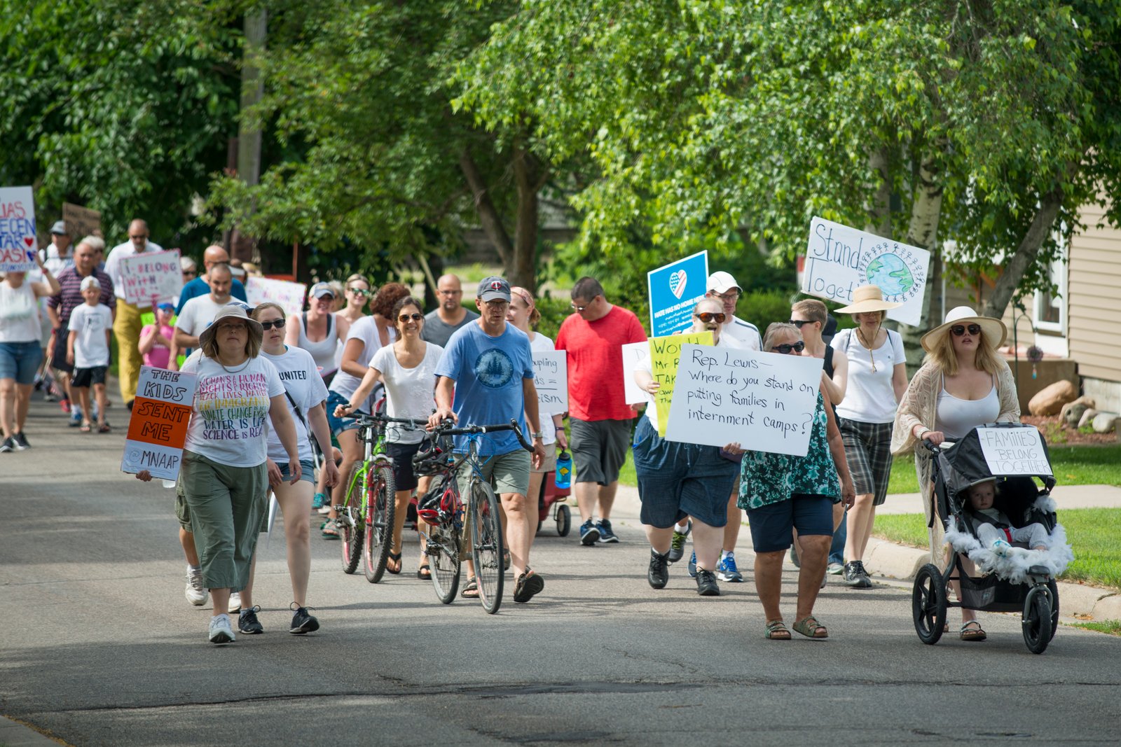 Community members walking together with signs supporting immigrant families in Northfield, Minnesota